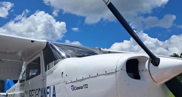Cessna 172 do Aeroclube de Canela com logo na fuselagem, estacionado em dia ensolarado, hélice e motor em detalhe