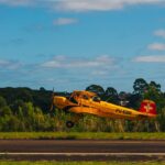 Festejos do 73º aniversário do Aeroclube de Canela no pátio do aeroclube com pessoas se divertindo, aviões chegando e saindo