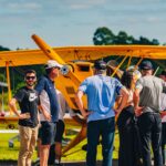 Festejos do 73º aniversário do Aeroclube de Canela no pátio do aeroclube com pessoas se divertindo, aviões chegando e saindo