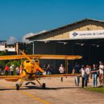 Festejos do 73º aniversário do Aeroclube de Canela no pátio do aeroclube com pessoas se divertindo, aviões chegando e saindo