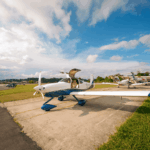 Festejos do 75º aniversário do Aeroclube de Canela no pátio do aeroclube com pessoas se divertindo, aviões chegando e saindo