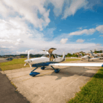 Festejos do 75º aniversário do Aeroclube de Canela no pátio do aeroclube com pessoas se divertindo, aviões chegando e saindo