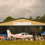 Festejos do 75º aniversário do Aeroclube de Canela no pátio do aeroclube com pessoas se divertindo, aviões chegando e saindo