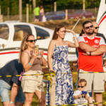 Festejos do 75º aniversário do Aeroclube de Canela no pátio do aeroclube com pessoas se divertindo, aviões chegando e saindo