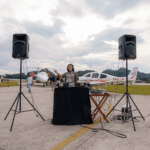 Festejos do 75º aniversário do Aeroclube de Canela no pátio do aeroclube com pessoas se divertindo, aviões chegando e saindo